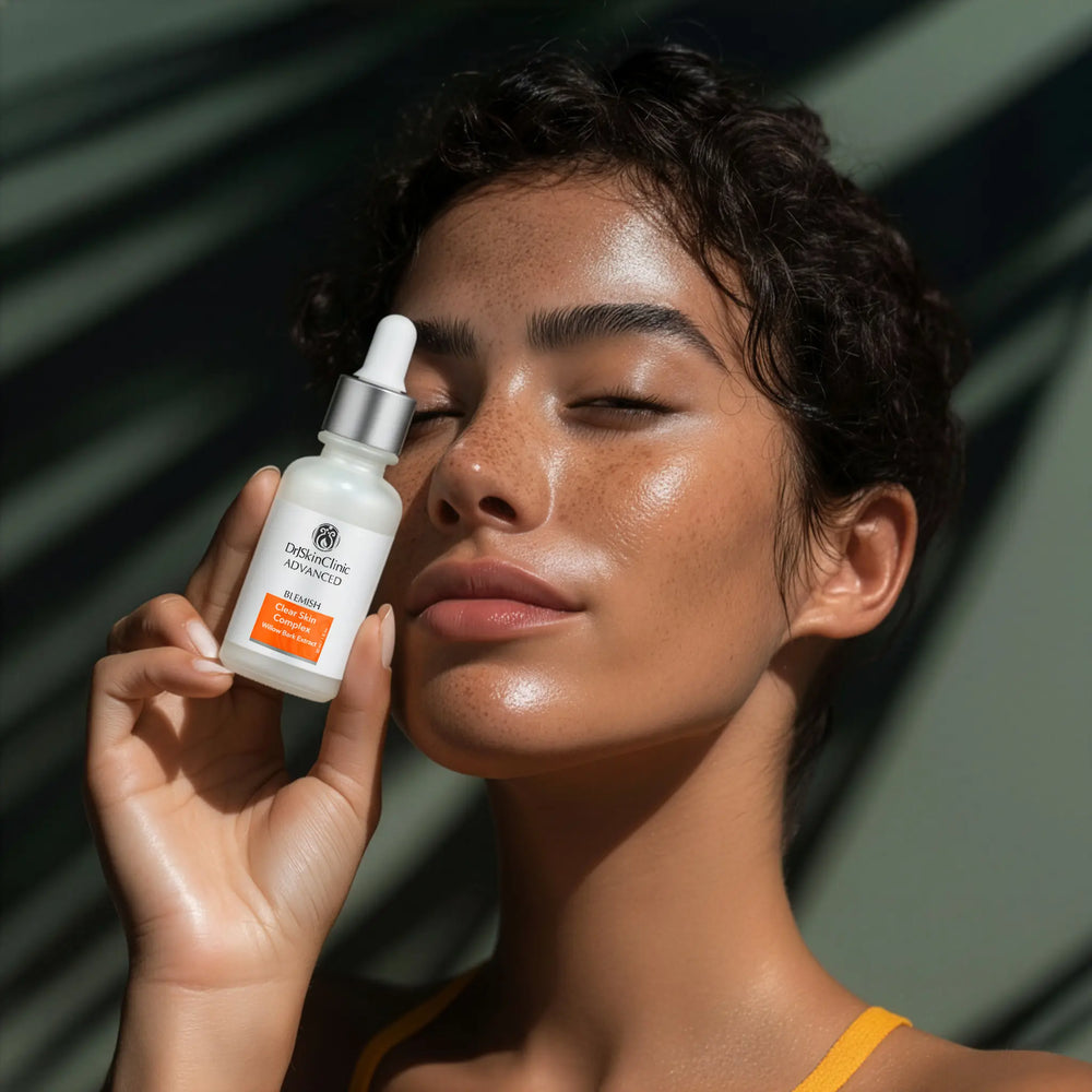 Model holding DrSkinClinic Advanced Blemish Clear Skin Complex with Willow Bark Extract serum, showcasing clear radiant skin in natural light