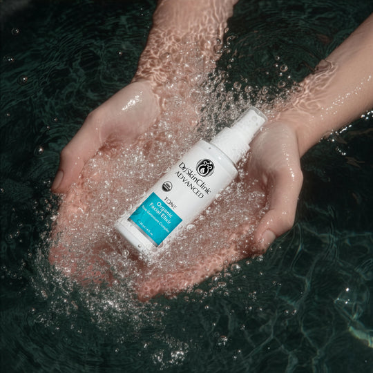 DrJSkinClinic Advanced Tone Organic Facial Elixir held in hands surrounded by water, highlighting refreshing USDA Organic facial toner with Rose Geranium Complex