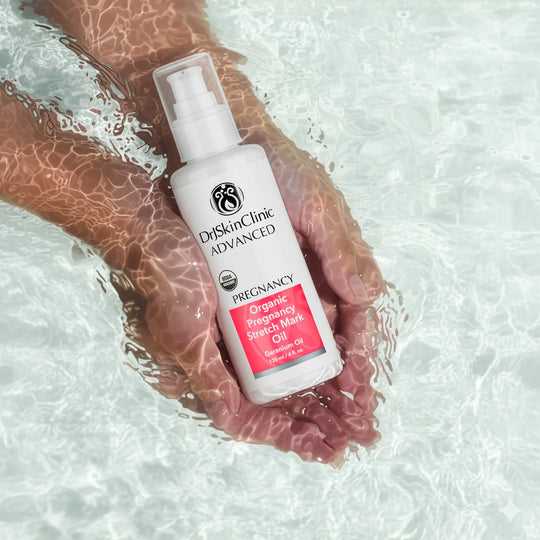 Hand holding DrSkinClinic Advanced Organic Pregnancy Stretch Mark Oil with Geranium Oil in water, showcasing product texture and hydration theme